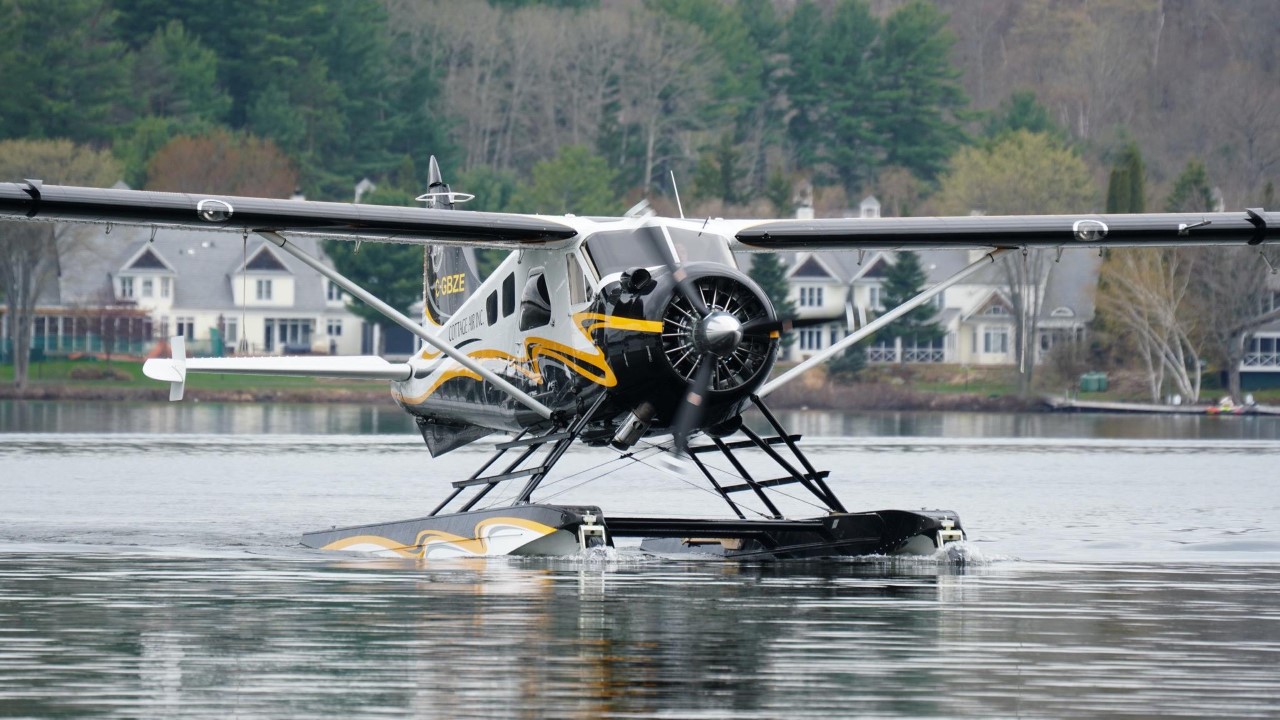 A small plane is flying over the water.